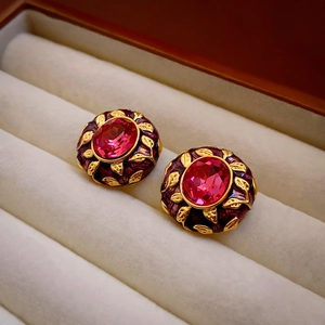 Macro shot of vintage style gold earring with pink gemstone and purple enamel in a box