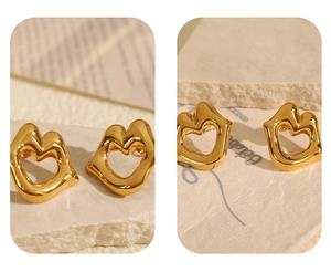 Macro detail of 18k gold plated stainless steel heart earrings on a stone background