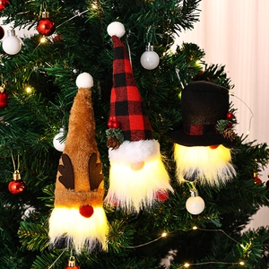 Three glowing Christmas gnome plush ornaments hanging on a festive tree with LED lights