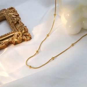 Elegant 18k gold plated titanium steel snake chain necklace with beads on white silk