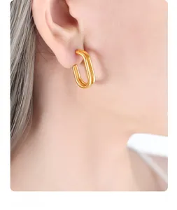 Detail of model wearing double oval gold drop earrings with minimalist geometric design