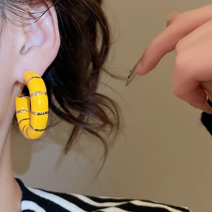 Detail view of vintage C-shaped yellow enamel hoop earrings on model with gold accents