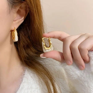 Retro geometric U-shaped gold earrings with cream resin inlay shown on model