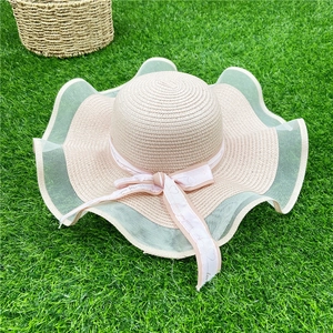 Détail d'un chapeau de paille avec bord en dentelle ondulée et ruban 'love you forever' sur herbe