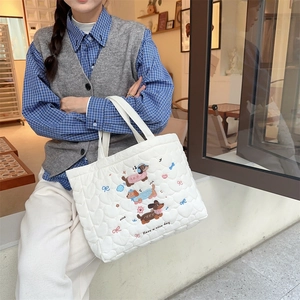 Close-up of white quilted handbag with heart stitching and cute sausage dog embroidery