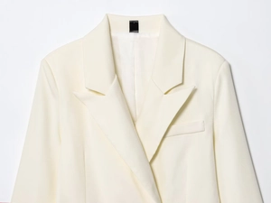 Detailed peak lapel and neck label of a creamy white double-breasted long blazer
