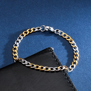 Dettaglio di bracciale a catena cubana bicolore oro e argento con chiusura a moschettone