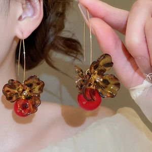 Detail of leopard print flower earrings with red pearl pendant on model ear