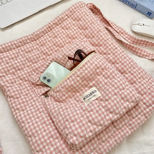 Detailed heart-quilted texture on a pink checkered bag with functional front zipper pocket