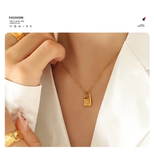 Close-up of 18k gold plated lock pendant necklace with starburst zircon and wide rings