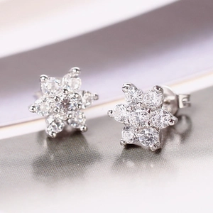 Detailed macro view of silver flower stud earrings with sparkling cubic zirconia stones
