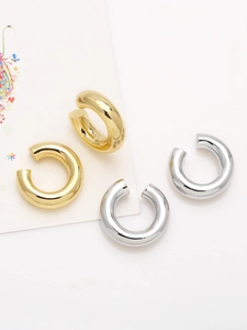Detail of chunky C-shaped ear cuffs in polished 18k gold and silver plated finish
