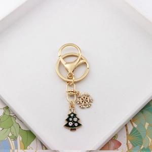 Detailed view of Christmas tree and snowflake charms with inlaid rhinestones on a gold keychain