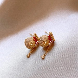Gros plan de boucles d'oreilles dorées avec sac de chance serti et pompons délicats