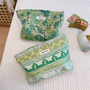 Detail of green floral jacquard fabric cosmetic bags with simple wish woven label