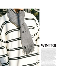 Close-up of grey tassel scarf with cashmere label and winter striped sweater outfit