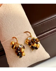 Macro detail of tiger eye and zircon grape-shaped earrings on jewelry pillow
