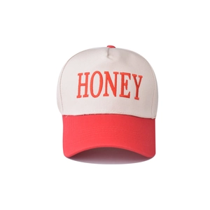 Detail of red HONEY embroidery on white and red color-block cotton baseball cap