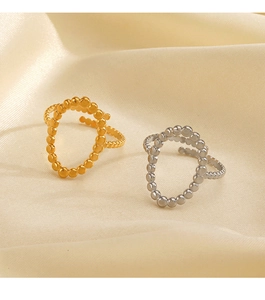 Dettaglio degli anelli a sfere oro e argento su sfondo di seta beige naturale
