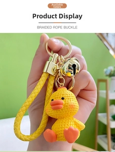 Close-up of yellow resin duck keychain with braided rope strap and golden bell detail
