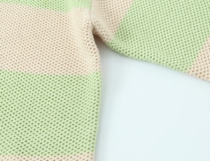Close-up of waffle-knit texture and light green striped stitching on this knit sweater