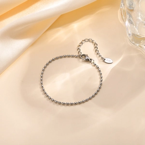Detailed macro view of silver steel beaded bracelet featuring K18 engraved metal tag