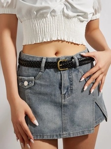 Close-up of black braided belt with gold buckle worn with denim skirt and white top