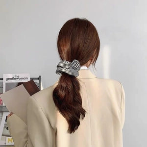 Elegant houndstooth scrunchie hair tie shown on a woman wearing a beige blazer suit