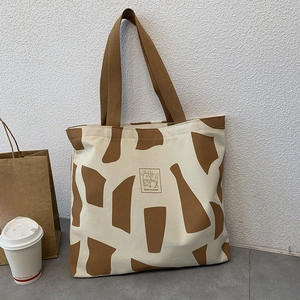 Detail of minimalist canvas tote with rabbit illustration and sturdy brown handles
