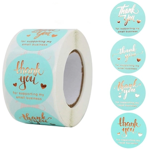 Macro detail of mint green thank you stickers with rose gold foil lettering on a roll