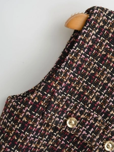 Close-up of textured tweed fabric with multi-color weave and embossed gold metal buttons