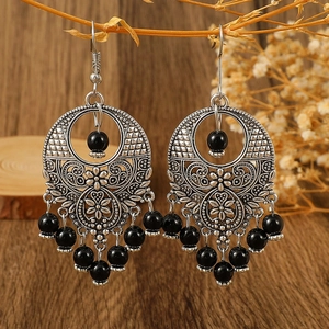 Detail of vintage bohemian silver hollow earrings with ethnic black bead tassels