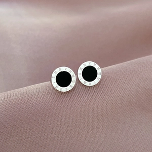 Detailed close-up of clover stud earrings with black inlay and Roman numeral engravings