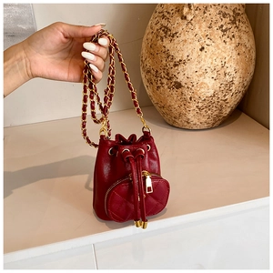 Detail of red quilted mini bucket bag with chain strap and drawstring closure