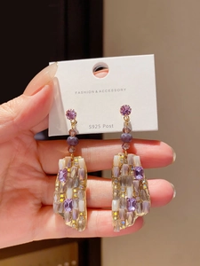 Detail showing square purple crystals on S925 silver post earrings held on a card