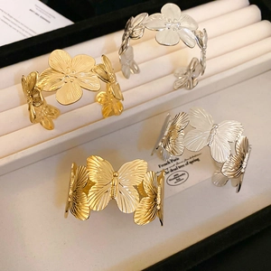 Textured metal open bangle featuring hollow flower and butterfly motifs in gold and silver