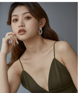 Close-up of sparkling sunflower-shaped zircon earrings worn on a model against grey backdrop