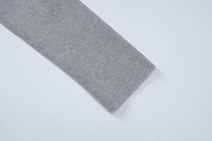 Close-up detail of grey ribbed knit fabric texture on the long sleeves of the polo dress