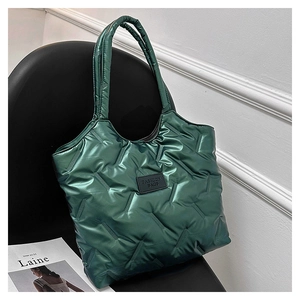 Detail of green quilted puffer tote bag with black fashion label on a chair