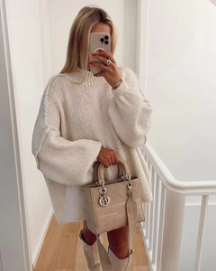Gros plan sur un pull en maille blanc oversize avec un sac brodé beige et bottes