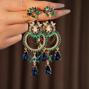 Gros plan de boucles d'oreilles vintage dorées avec strass bleus et verts en gouttes
