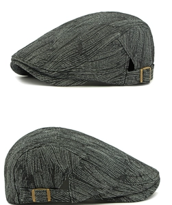 Macro detail of charcoal grey woven fabric and brass metal buckle on the flat cap