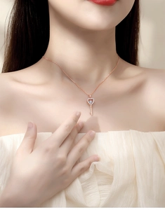 Close-up of rose gold heart-key moissanite necklace worn on a woman's neck