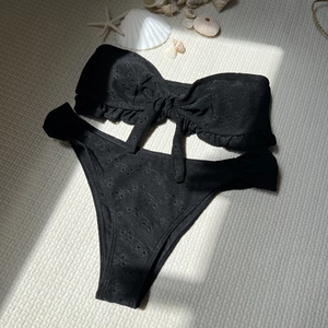 Detailed view of black eyelet embroidery and ruffle hem on a strapless bikini set