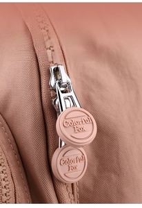Detailed macro of smooth metal zipper and silicone pulls on the pink nylon backpack