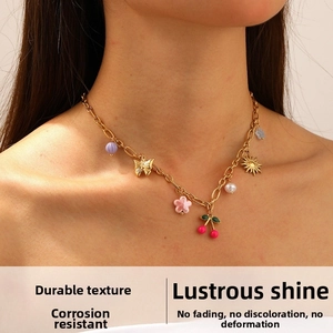 Detail of a gold necklace with cherry, flower and butterfly charms on a model