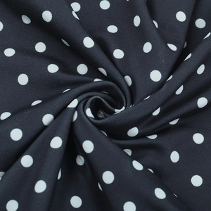 Gros plan sur un tissu à pois noirs et blancs avec texture lisse et plis souples