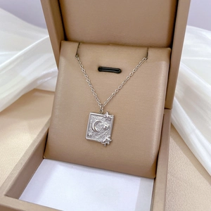 Detailed view of silver celestial pendant with sun and moon engravings in a gift box