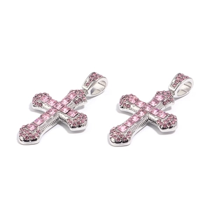Close-up of silver cross pendants with pink crystal rhinestones for DIY jewelry