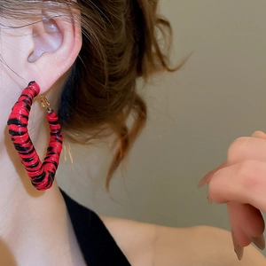 Gros plan détaillé d'un mannequin portant des créoles à motif léopard rouge et noir